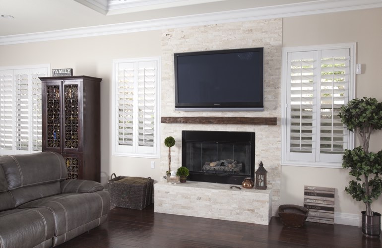 White plantation shutters in a New Brunswick living room with dark hardwood floors.